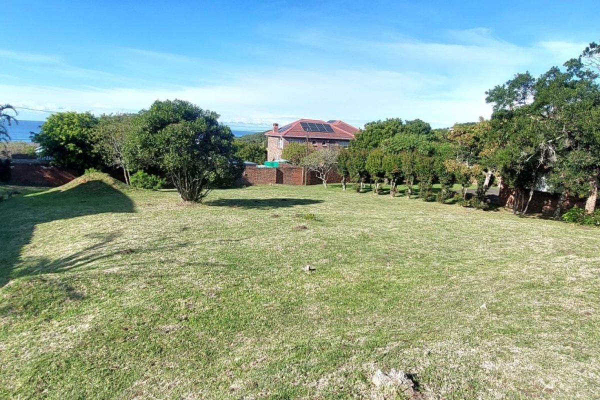 A spacious, well-maintained residential garden plot featuring established trees, a manicured lawn, and perimeter boundary walls.