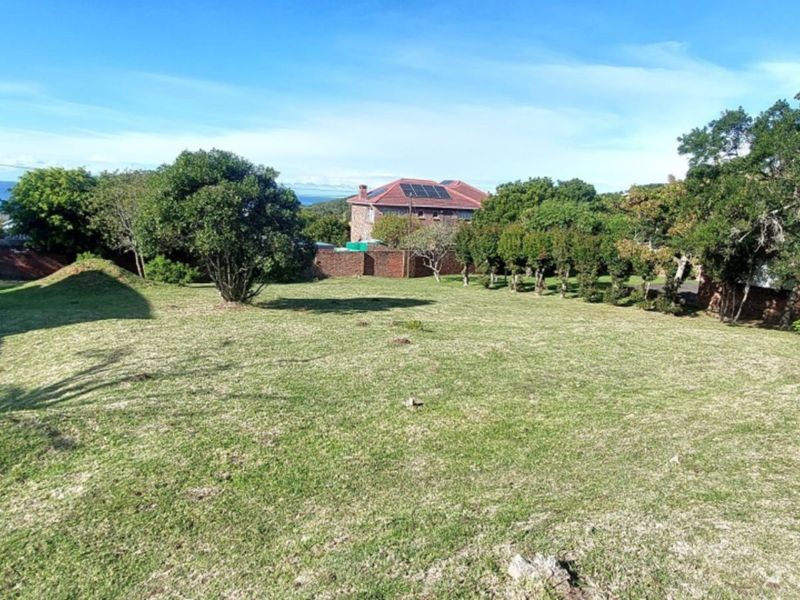 A spacious, well-maintained residential garden plot featuring established trees, a manicured lawn, and perimeter boundary walls.