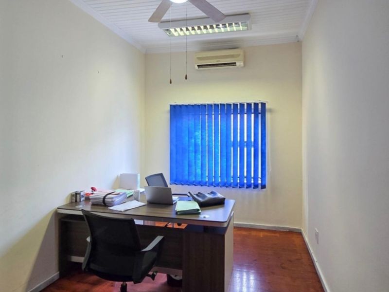A functional home office featuring timber flooring, air conditioning, and vertical blinds, providing a practical workspace with good natural light.