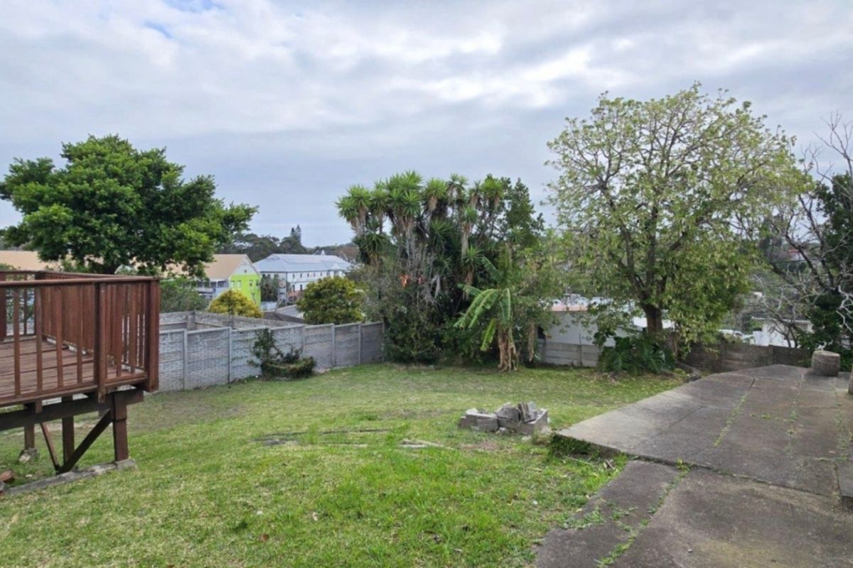 Rear garden area featuring a raised wooden deck, concrete patio space, and perimeter boundary walling.
