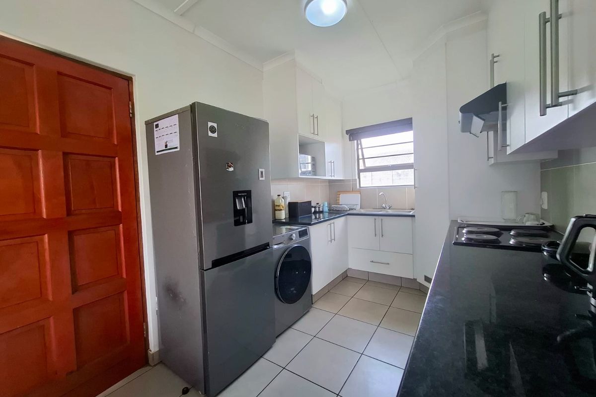 Compact kitchen featuring white cabinetry, dark granite countertops, tiled flooring, and integrated cooking appliances.