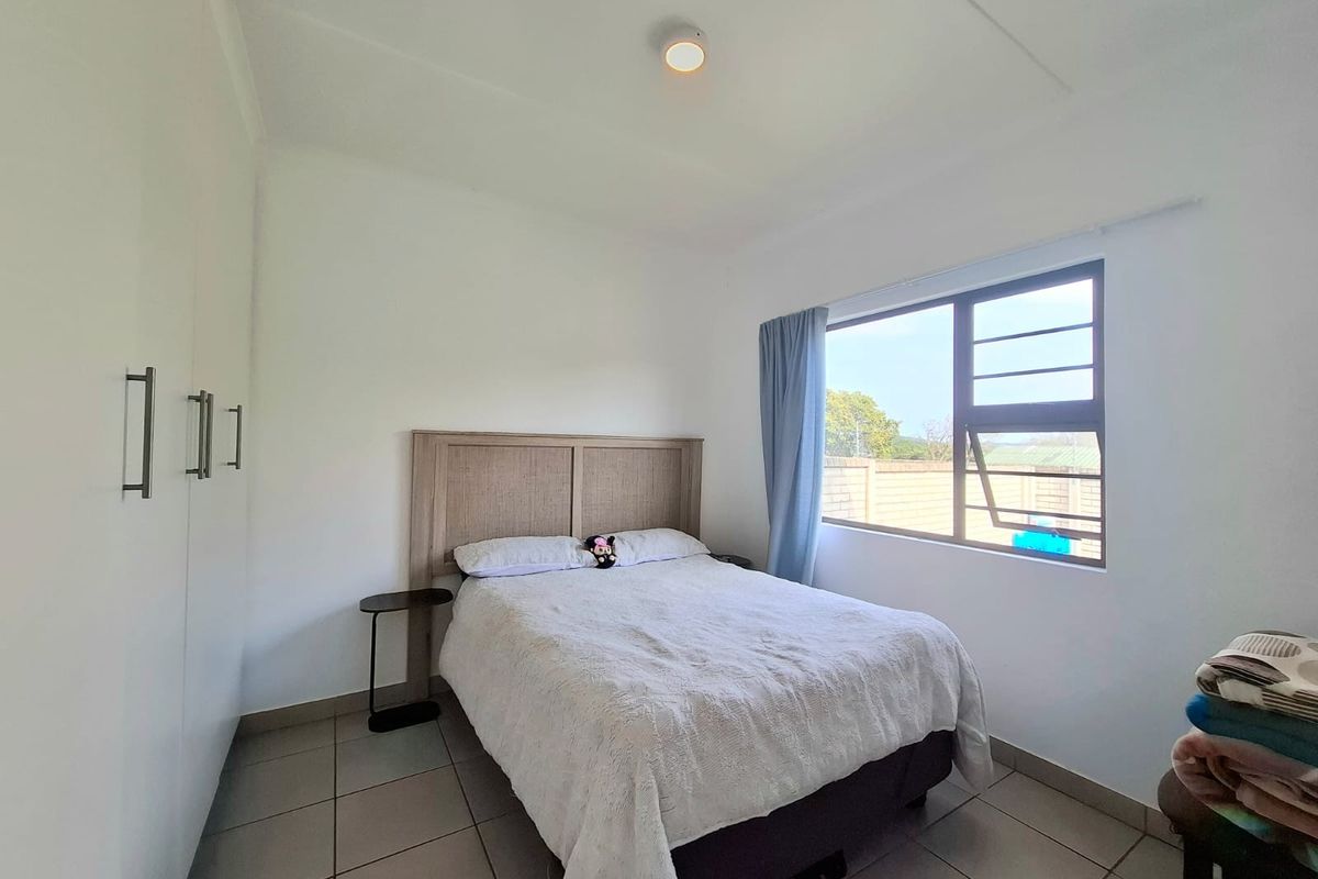 A functional bedroom featuring tiled flooring, built-in cupboards, and an aluminium window frame providing natural light.
