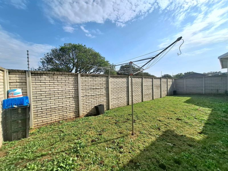 A private rear garden featuring a brick boundary wall with electric fencing and a rotary clothesline.
