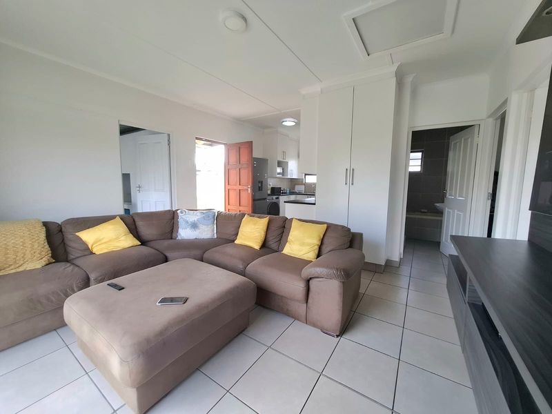 Open-plan living area featuring tiled flooring, built-in storage cupboards, and direct access to the kitchen and adjacent rooms.