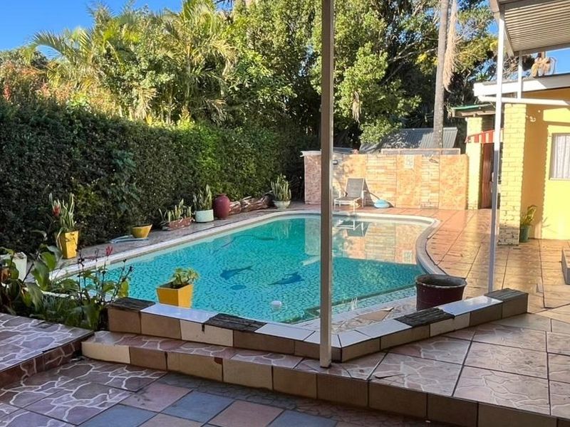 Outdoor pool area featuring a swimming pool, tiled patio space, and brick boundary wall, providing a functional outdoor entertainment area.