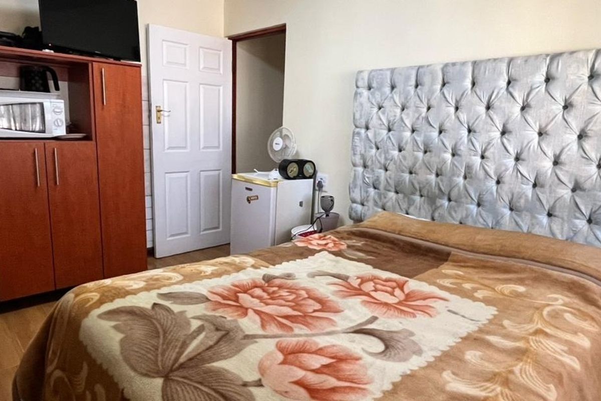 A functional bedroom featuring laminate flooring and a built-in cupboard, providing essential storage space within the guest house accommodation.