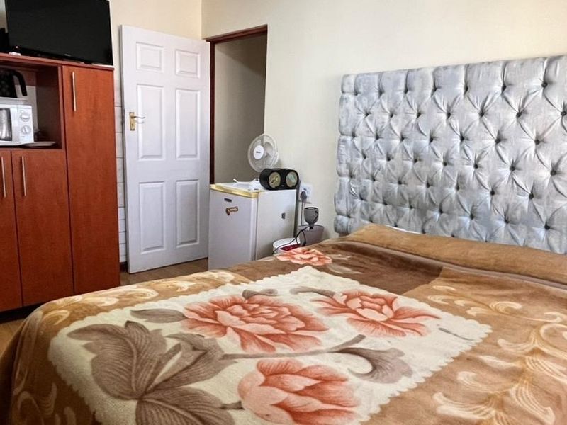 A functional bedroom featuring laminate flooring and a built-in cupboard, providing essential storage space within the guest house accommodation.
