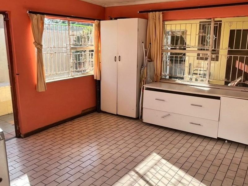 A bedroom featuring tiled flooring, security bars on windows, and built-in cabinetry, requiring cosmetic updates to improve its overall condition and appeal.