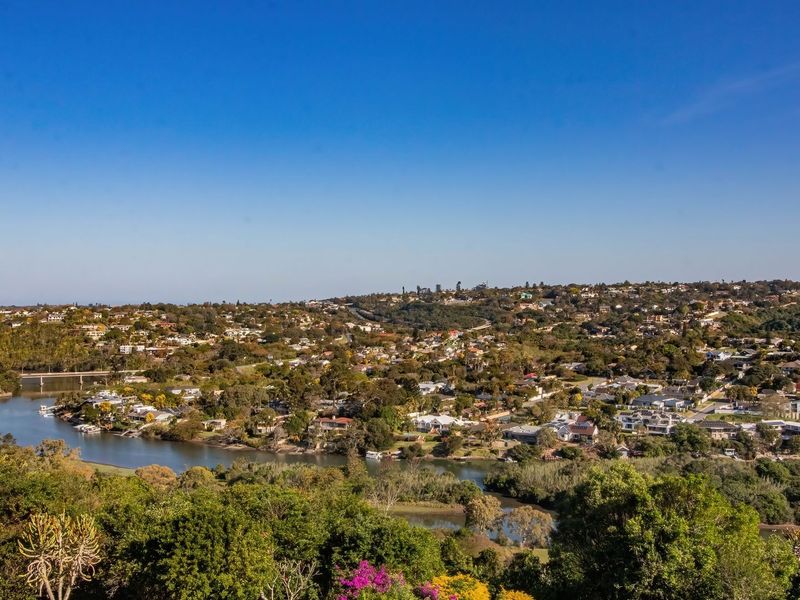 A wide-angle elevated view overlooking a river, lush green landscape, and a residential neighborhood.