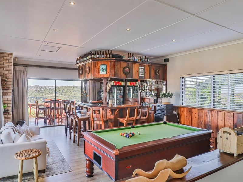 Spacious entertainment room featuring a built-in wooden bar, pool table area, and sliding glass doors opening to an outdoor deck with scenic views.