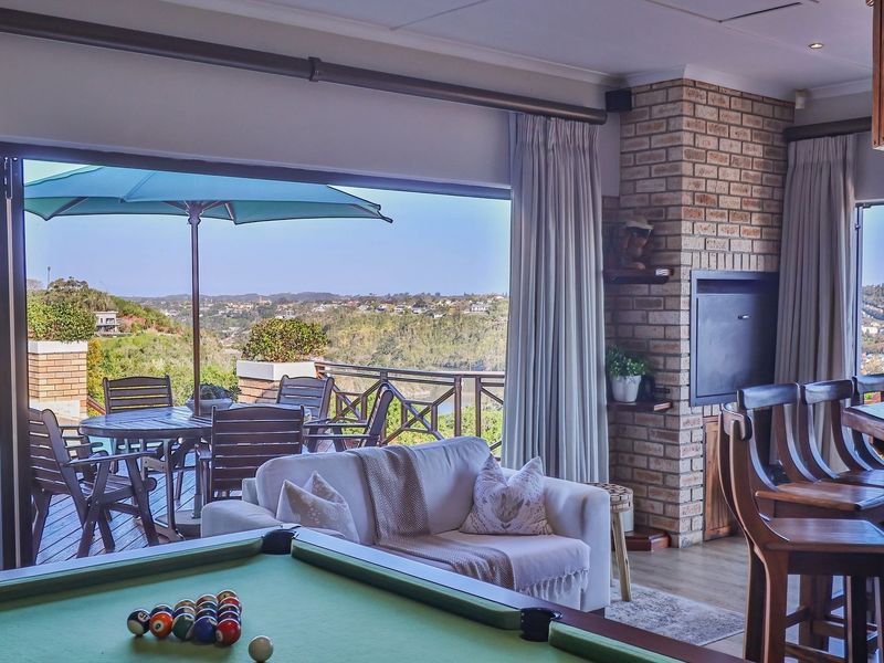 Spacious living area featuring a built-in fireplace with exposed brickwork, opening onto a deck with scenic views through large sliding glass doors.