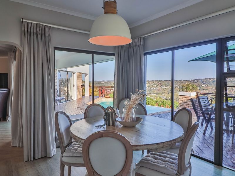 Bright dining area featuring large sliding glass doors that open onto a deck with pool and scenic landscape views.