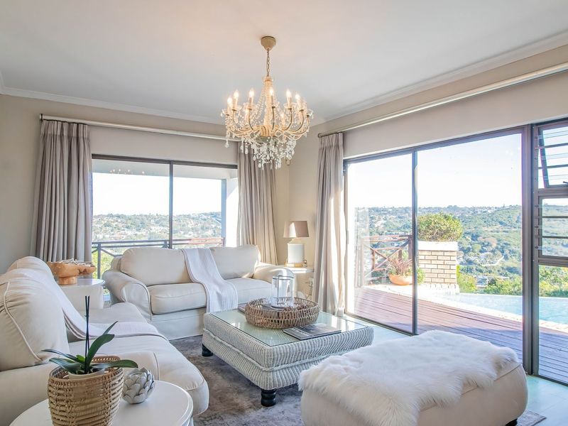 Bright and elegant living room featuring large sliding glass doors that open to a scenic outdoor deck and pool area.