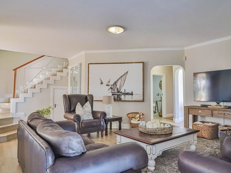 Spacious living room featuring a staircase with a modern railing, arched doorway, and neutral finishes, creating a comfortable and inviting atmosphere.
