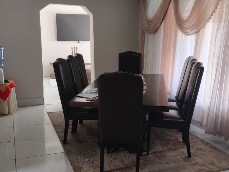 A dining room featuring tiled flooring and an arched entryway leading to an adjacent living space.