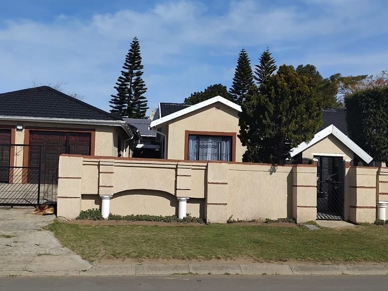Front view of the property featuring a perimeter wall, pedestrian gate, and a double garage with a tiled roof.