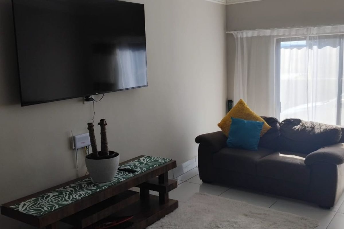 A living room featuring tiled flooring and a sliding glass door providing natural light.