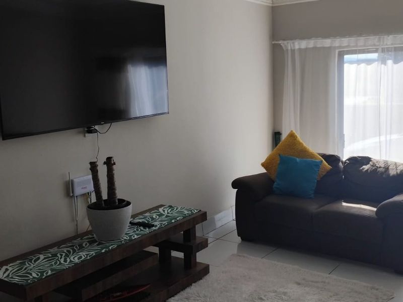 A living room featuring tiled flooring and a sliding glass door providing natural light.