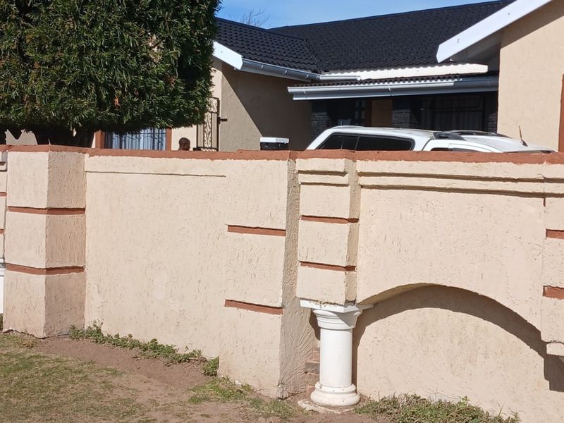 Front view of the property featuring a decorative perimeter wall with pillars and a tiled roof structure.