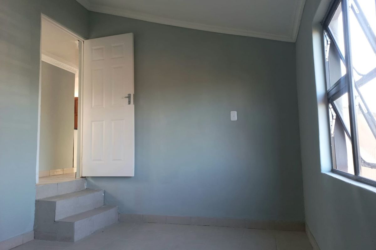 An empty bedroom featuring tiled flooring, neutral wall paint, and a stepped transition leading to an adjacent room.