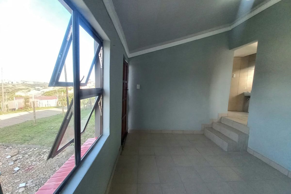 An empty living area featuring tiled flooring, large top-hung windows, and internal steps leading to an adjacent space.
