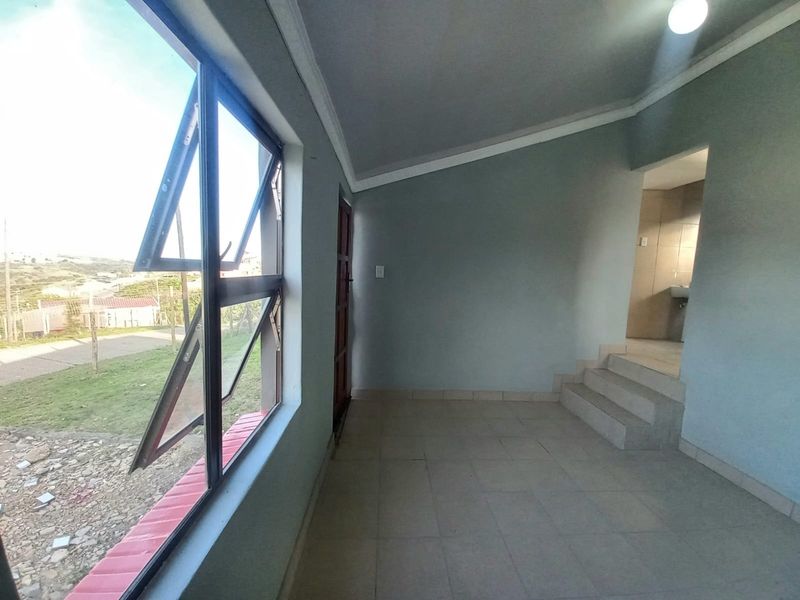 An empty living area featuring tiled flooring, large top-hung windows, and internal steps leading to an adjacent space.