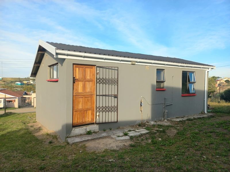 A view of the rear exterior of the house featuring a timber door with security gate, aluminium windows, and a tiled roof.