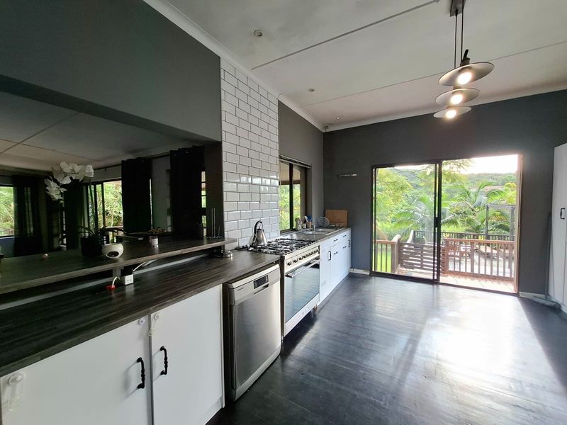 Modern kitchen featuring dark cabinetry, subway tile backsplash, gas stove, and direct access to an outdoor deck through sliding glass doors.