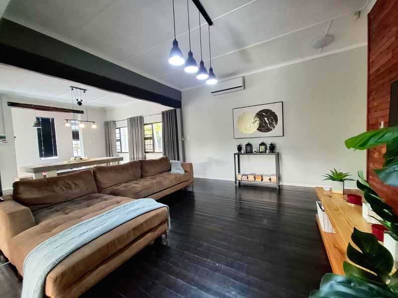 Spacious open-plan living area featuring dark timber flooring, exposed ceiling beams, and a split-system air conditioner, creating a warm and inviting atmosphere.