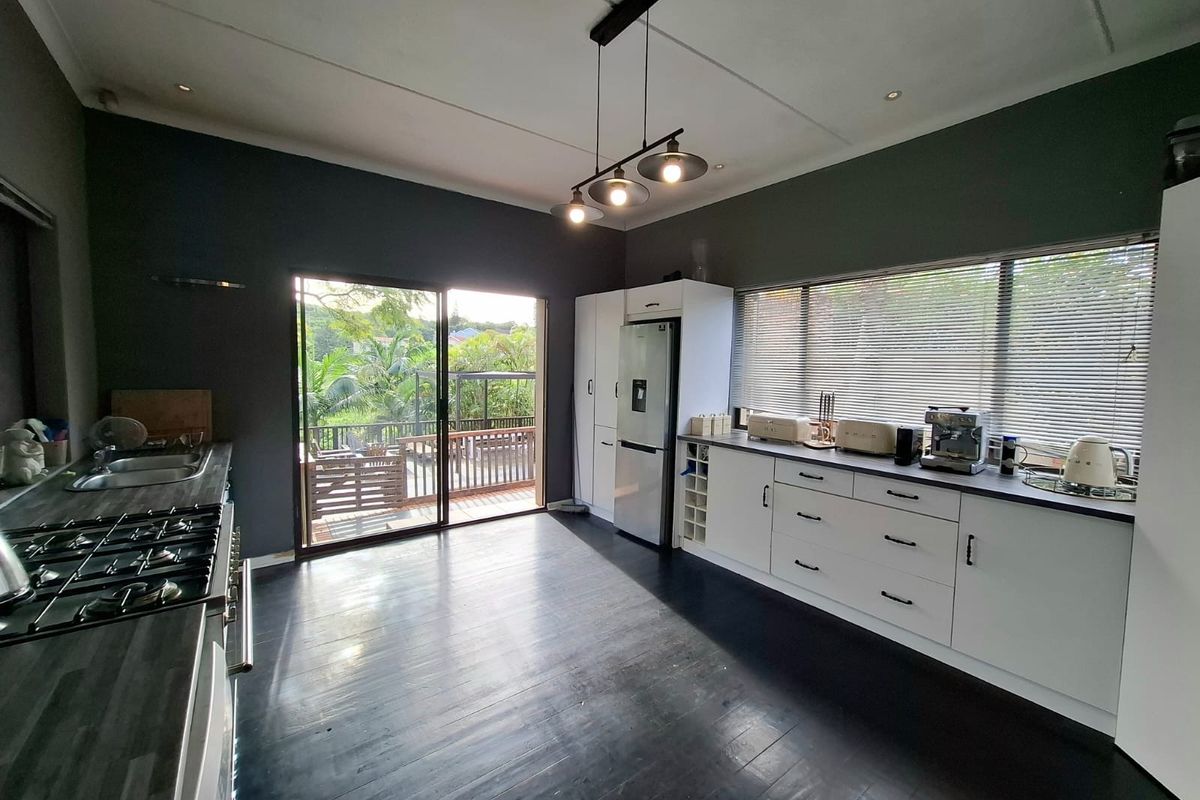 Modern kitchen featuring dark cabinetry, gas hob, built-in oven, and direct access to an outdoor deck through sliding glass doors.