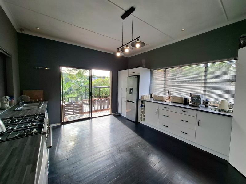 Modern kitchen featuring dark cabinetry, gas hob, built-in oven, and direct access to an outdoor deck through sliding glass doors.