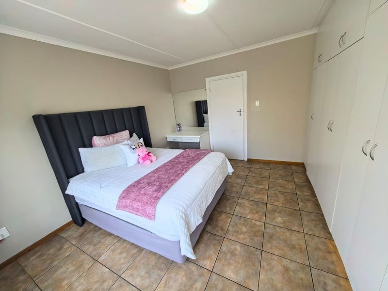 A bedroom featuring tiled flooring, built-in cupboards, and a coved ceiling, providing a functional and neutral living space.