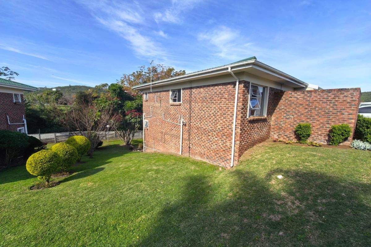 Rear view of the townhouse featuring a face brick exterior, pitched roof, and well-maintained garden space.