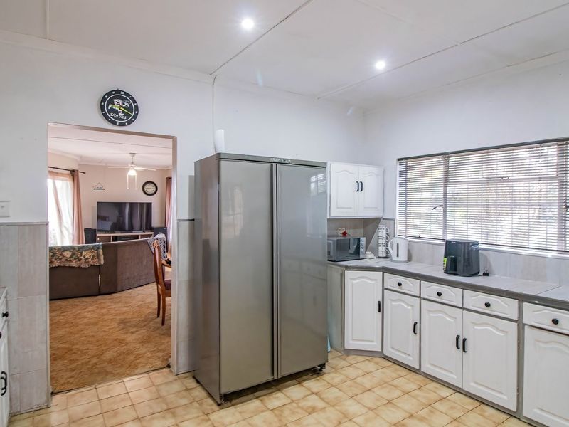 A functional kitchen featuring white built-in cabinetry, tiled flooring, and integrated cooking appliances, with an open flow into the adjacent living area.