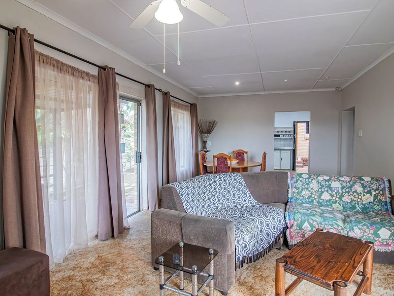 Spacious living room featuring a ceiling fan, carpeted flooring, and sliding glass doors providing access to the outdoor area.