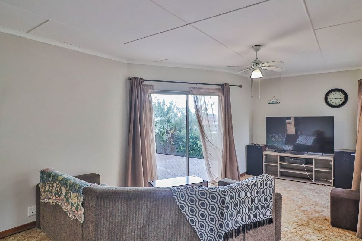 A living room featuring a ceiling fan, carpet flooring, and a sliding glass door providing access to the outdoor area.