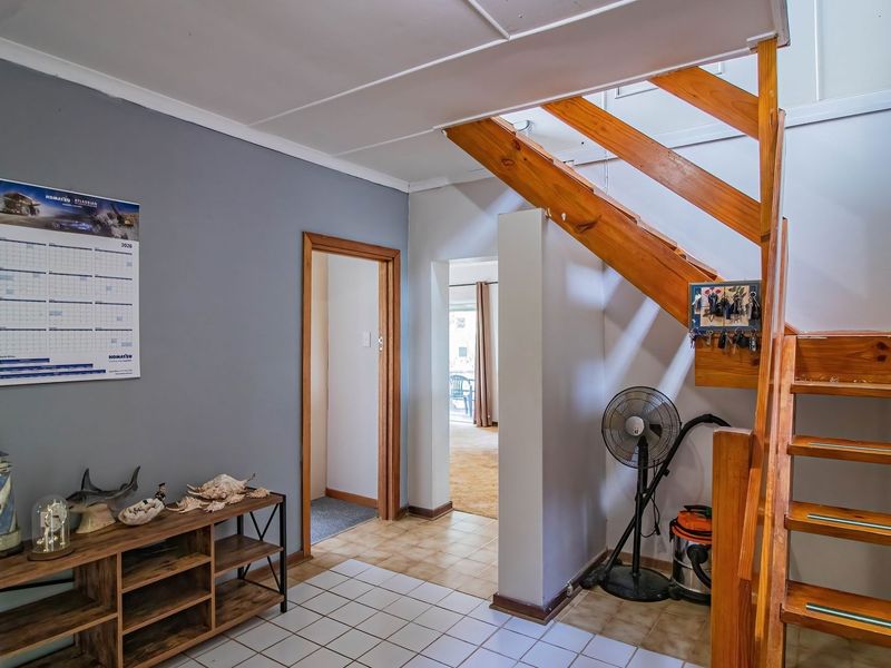 An entry area featuring a timber staircase and tiled flooring, providing access to adjacent rooms within the home.