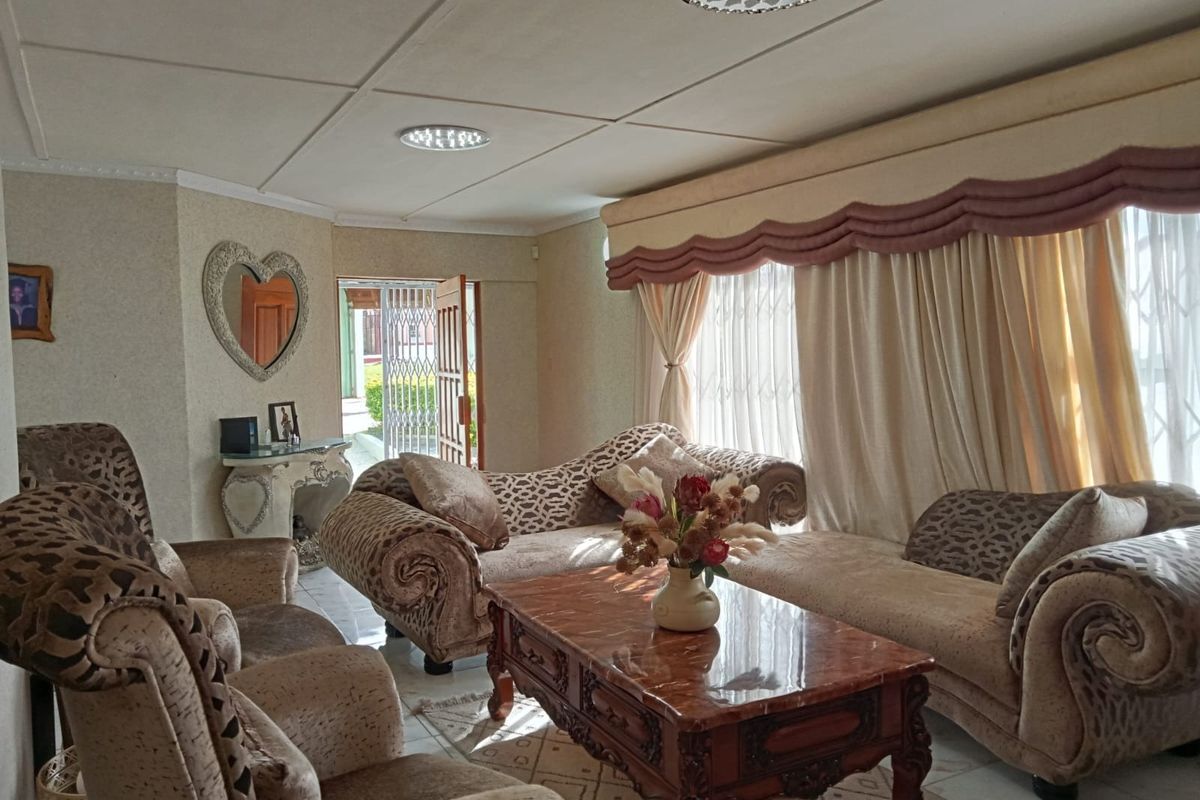 A living room featuring tiled flooring, ceiling lighting, and access to an exterior area through a security gate.