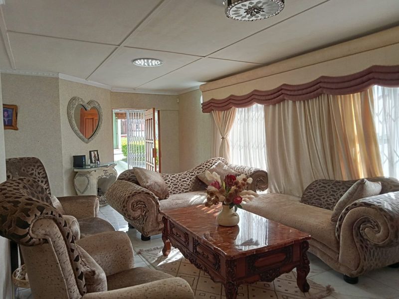 A living room featuring tiled flooring, ceiling lighting, and access to an exterior area through a security gate.