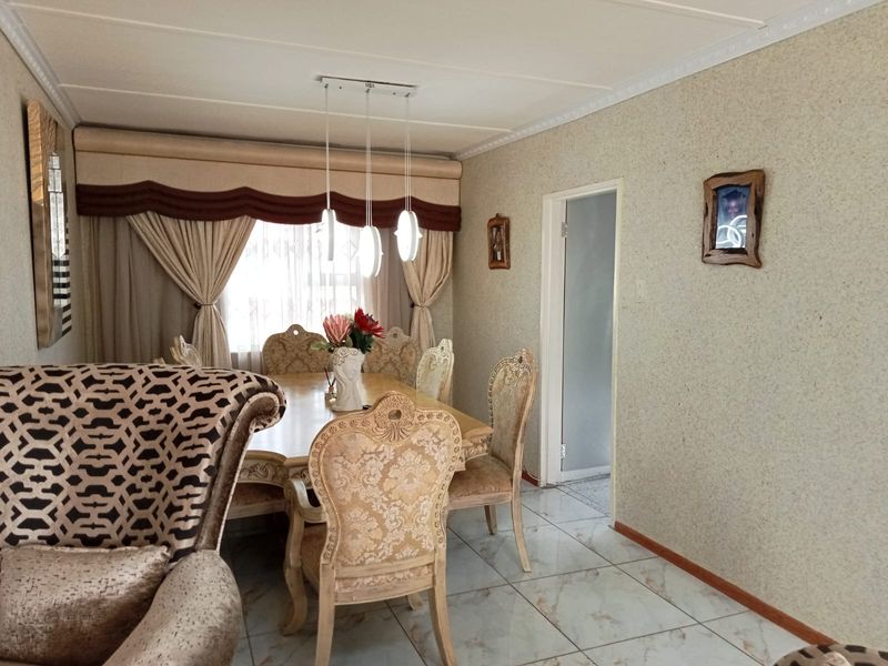 A dining room featuring tiled flooring, coved ceiling details, and modern pendant lighting, providing a functional space for family meals.
