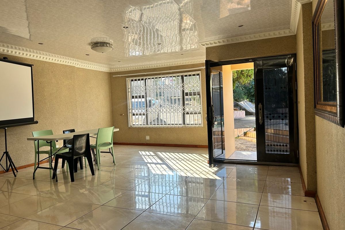 Spacious living area featuring polished tiled flooring, decorative ceiling cornices, and direct access to the exterior through a secure double door.