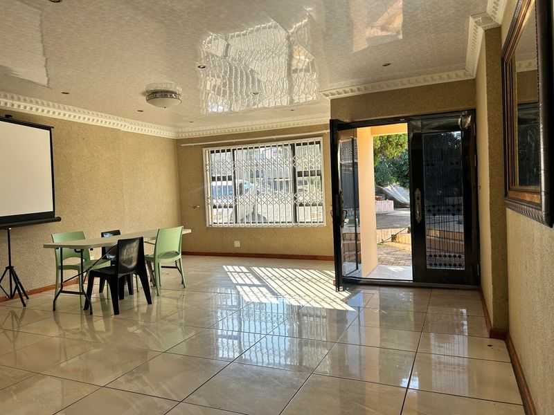 Spacious living area featuring polished tiled flooring, decorative ceiling cornices, and direct access to the exterior through a secure double door.