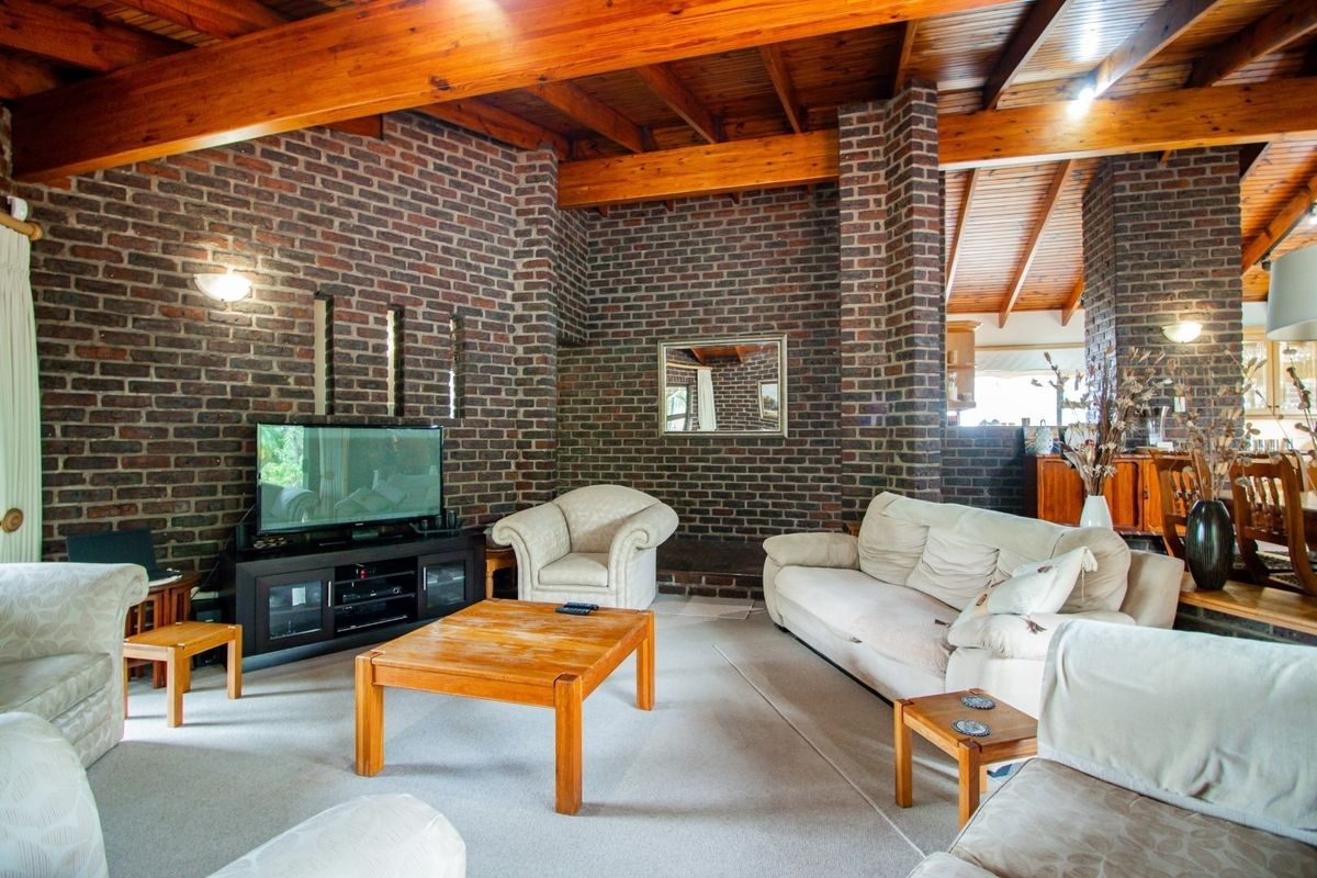 Spacious living room featuring exposed timber beam ceilings and characterful exposed brick walls, creating a warm and rustic atmosphere.