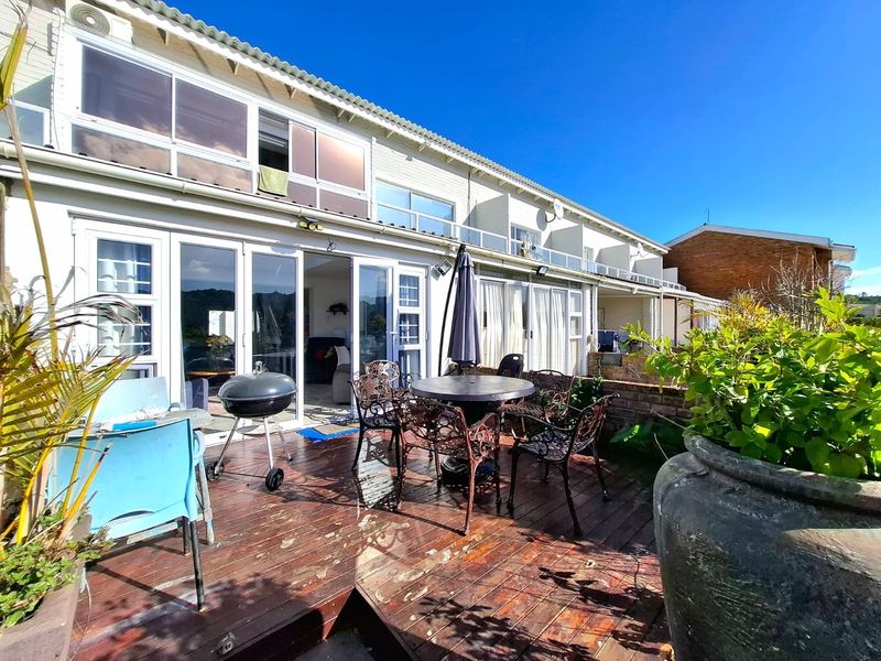 Rear exterior view of the townhouse featuring a timber deck patio area with direct access to the living space through sliding glass doors.