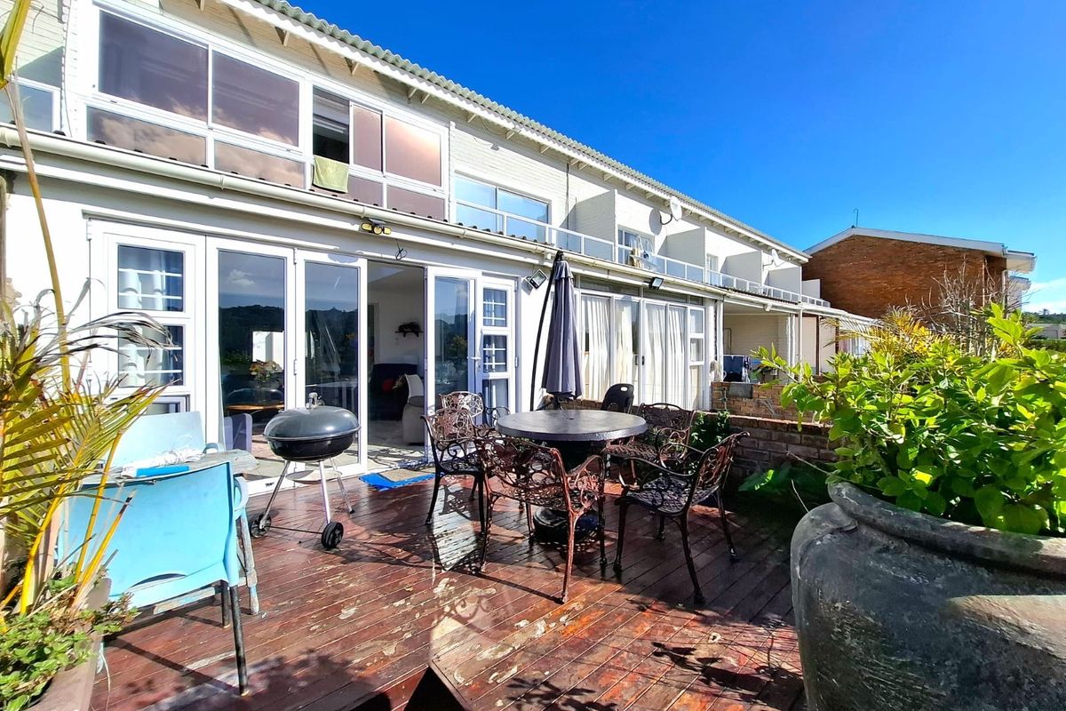 Rear exterior view of the townhouse featuring a timber deck patio area with direct access to the living space through sliding glass doors.