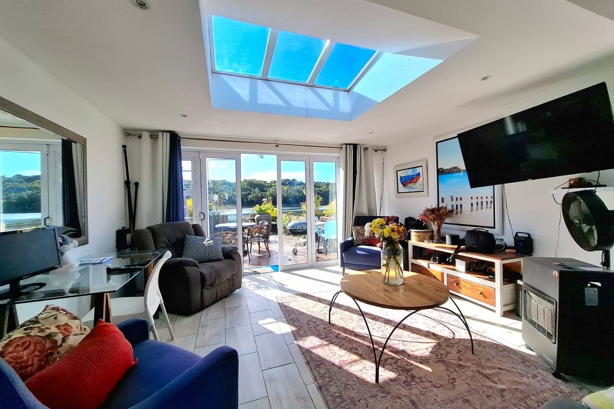 Bright living room featuring a large skylight, tiled flooring, and sliding glass doors that open onto an outdoor patio area.