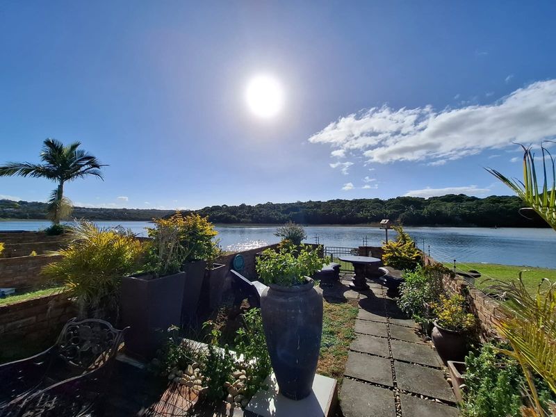 Outdoor patio area featuring a brick retaining wall and paved walkway, offering scenic waterfront views.