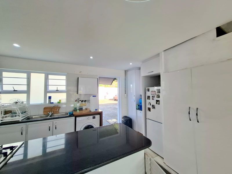 Functional kitchen featuring granite countertops, built-in cabinetry, and a double sink, with direct access to the exterior.