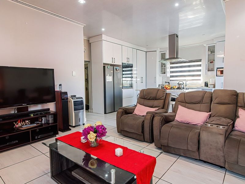 Open plan living area featuring tiled flooring, recessed lighting, and a modern kitchen with built-in cabinetry and stainless steel extractor fan.