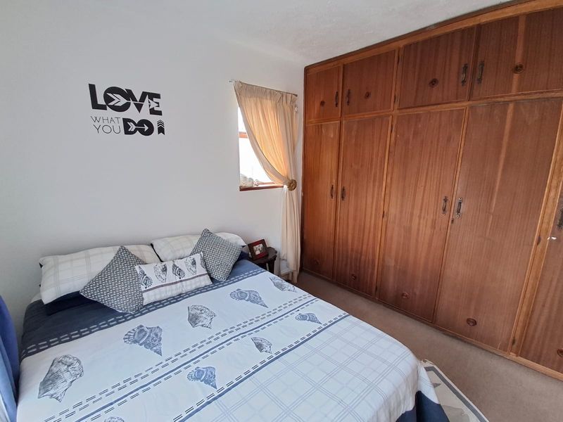 A bedroom featuring extensive floor-to-ceiling built-in wooden cupboards and a window with natural light.